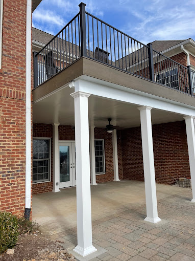 Two-story brick building with white columns and metal balcony railing