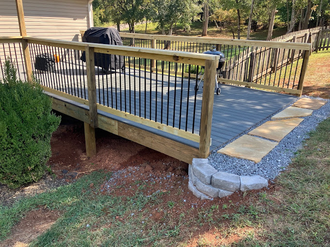 Wooden deck with metal railings leading to backyard with stone pathway