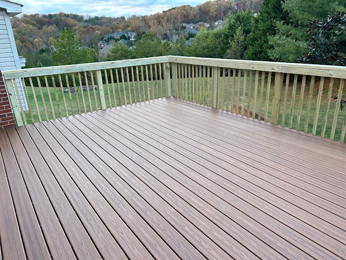 Wooden deck with railing overlooking forested neighborhood landscape