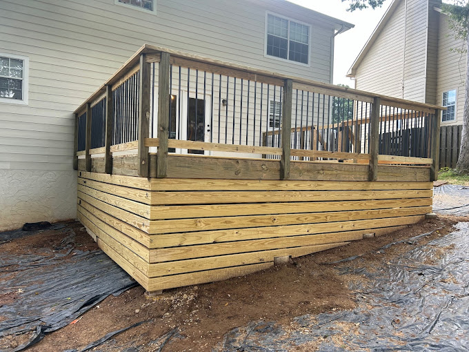 Newly constructed wooden deck attached to two-story house with metal railings
