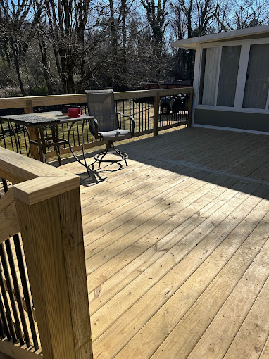 Wooden deck with metal chairs and railing, overlooking bare winter trees