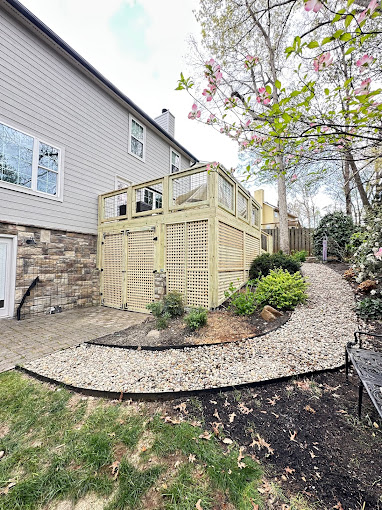 Landscaped backyard with stone pathway, privacy fence, and blooming tree