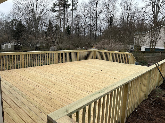 Newly constructed wooden deck with railing in backyard during winter