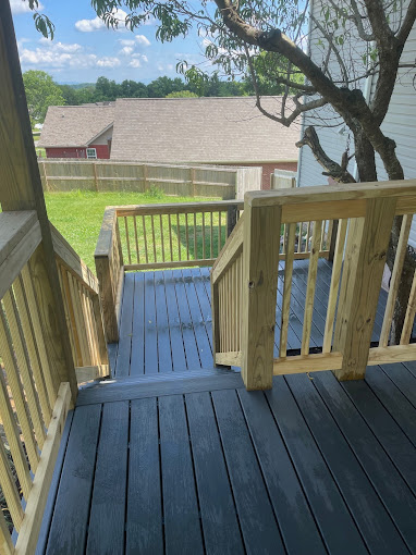 Wooden deck with view of green lawn and red barn in distance