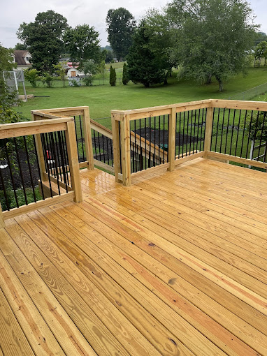New wooden deck with black metal spindles overlooking green backyard