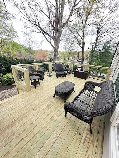 Wooden deck with outdoor furniture surrounded by trees and vegetation