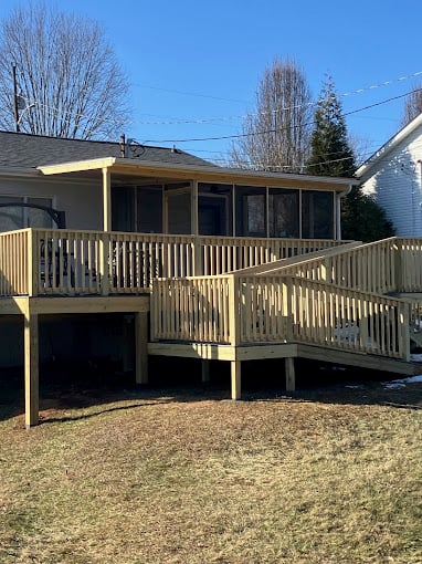Wooden deck with stairs attached to house on sunny winter day