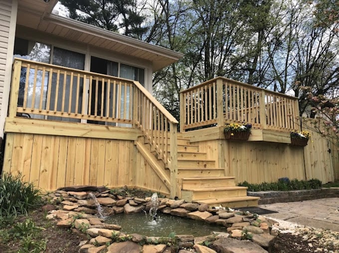 Wooden deck with stairs overlooking a small stone water feature garden